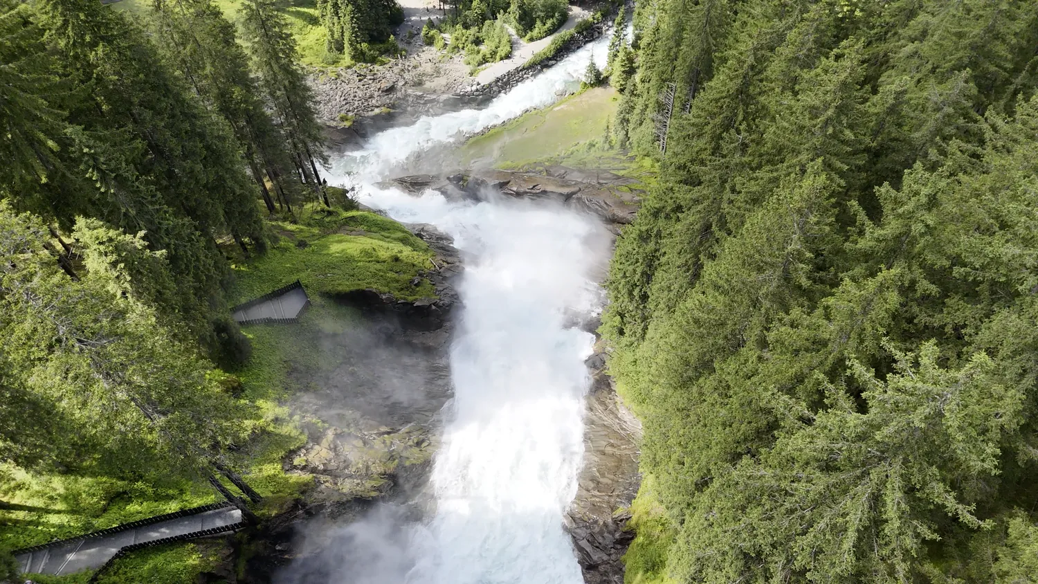 Drohnenaufnahme eines kraftvollen Wasserfalls in unberührter, bewaldeter Natur