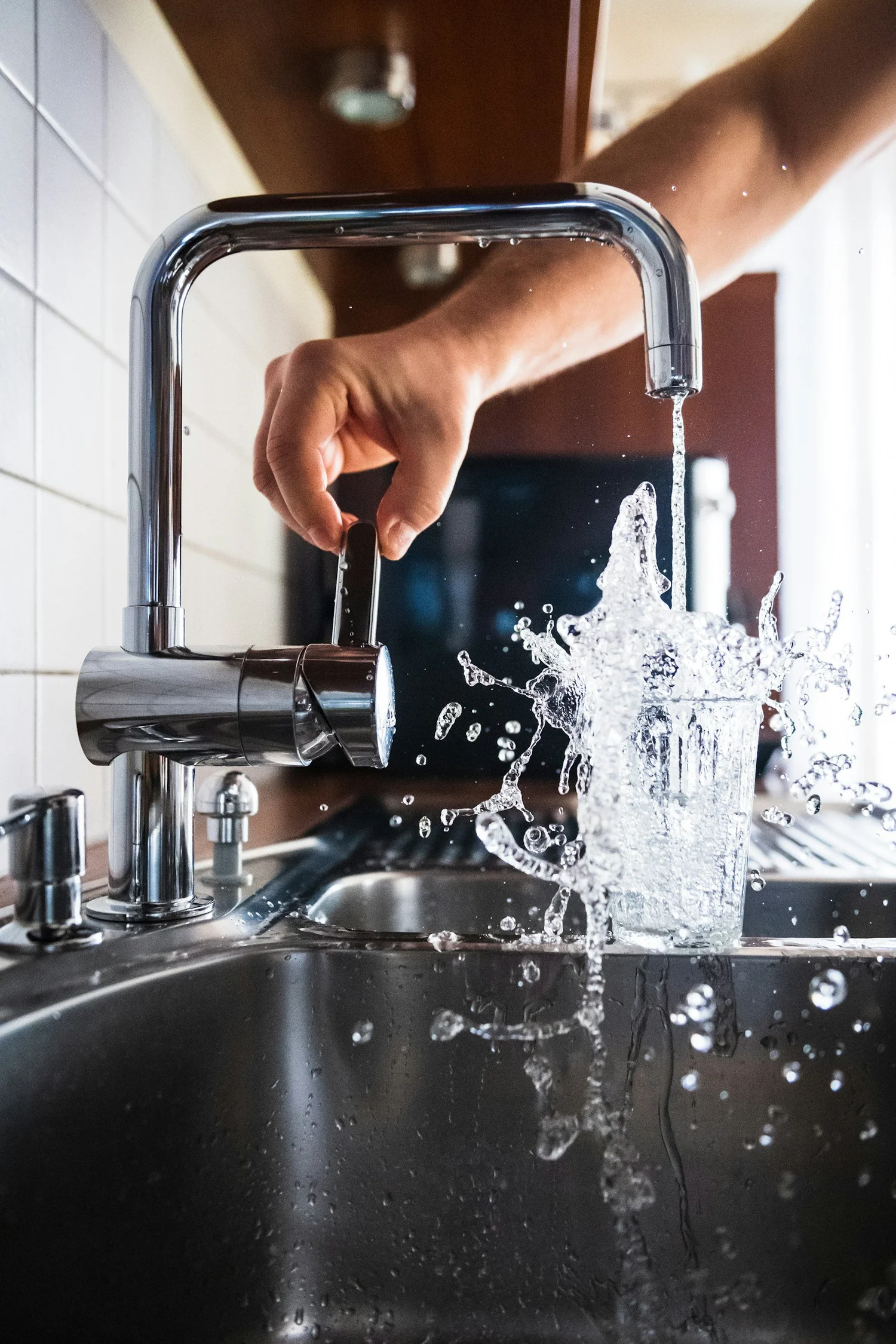 Frisches Wasser spritzt aus dem Wasserhahn in ein Glas, Trinkwasserqualität mit Eco Stolz